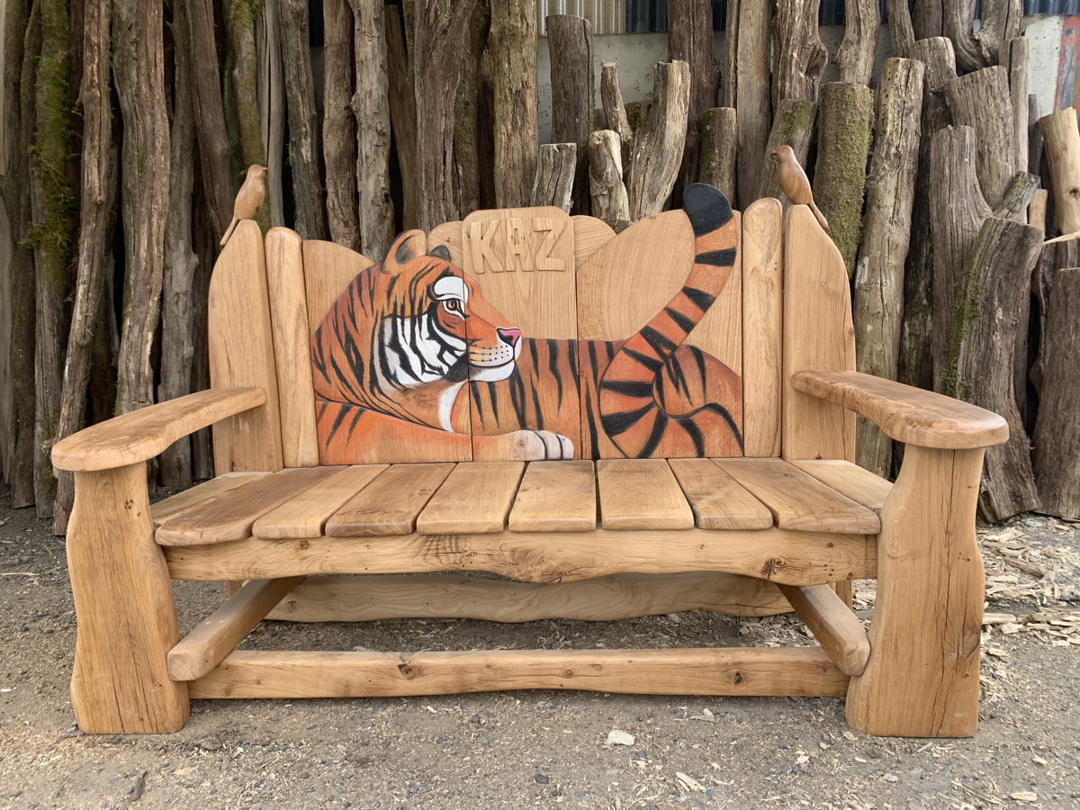 Banc rustique en bois avec un tigre sculpté, posé sur des rondins de bois