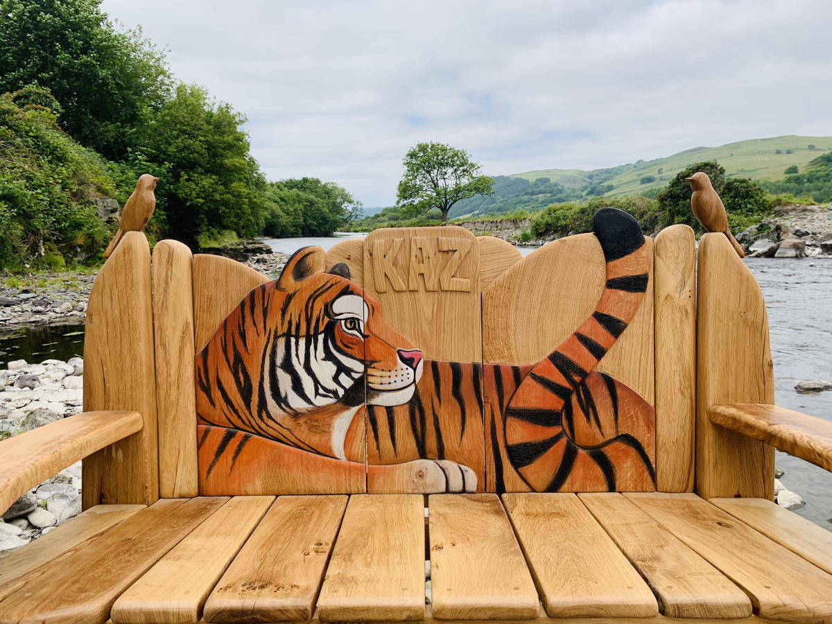 Tiger-themed wooden bench with scenic river backdrop