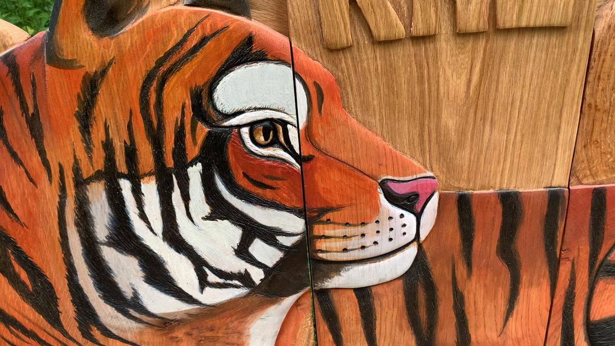 Close-up of tiger face carving on a wooden bench