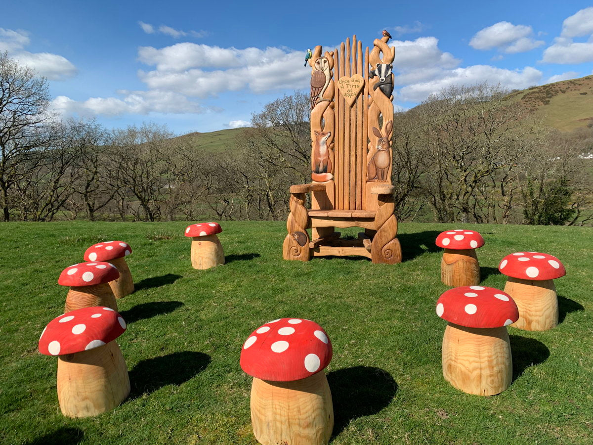 Installation extérieure avec tabourets en forme de champignon et chaise sculptée