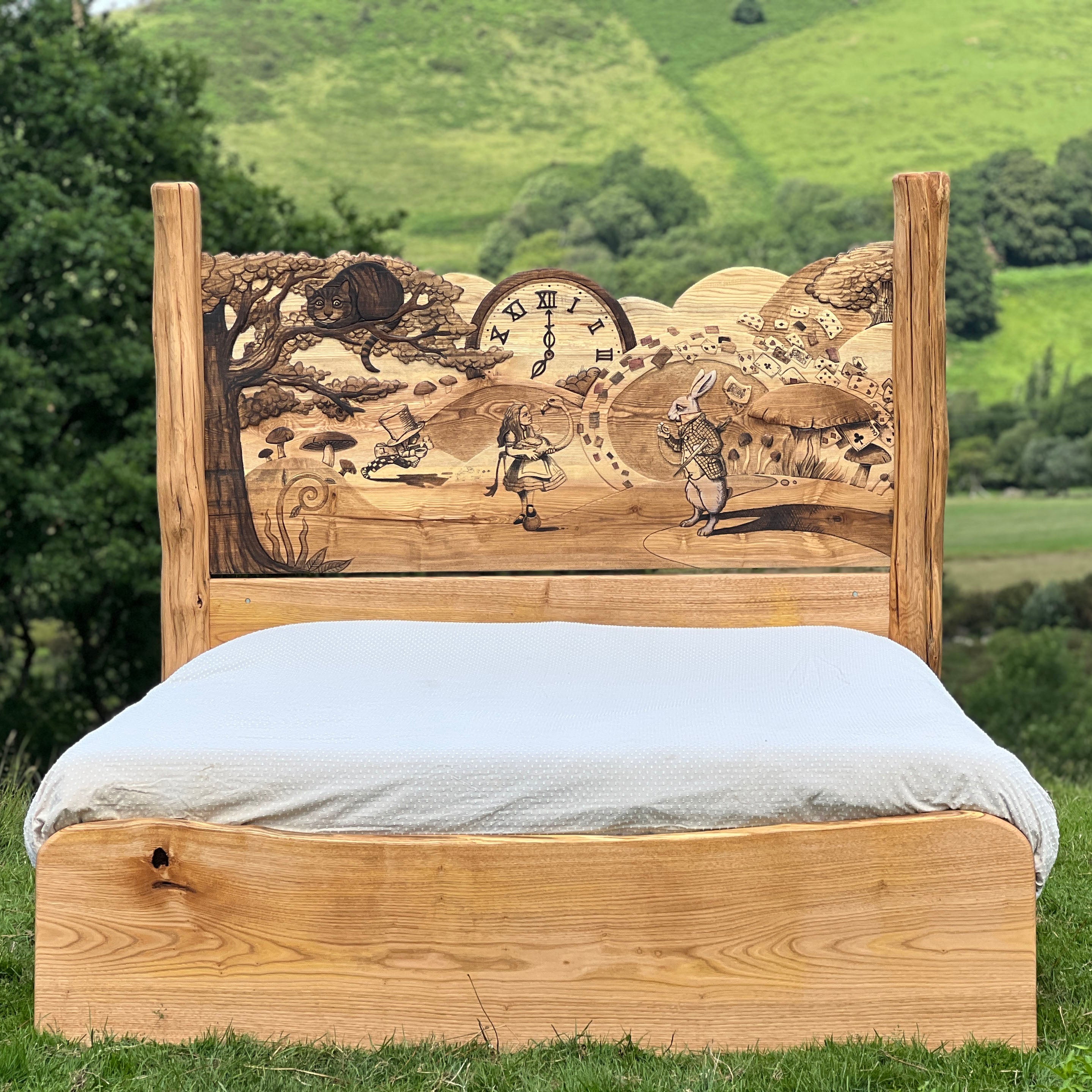 Front view of handcrafted Alice in Wonderland bed with carved wooden headboard in countryside