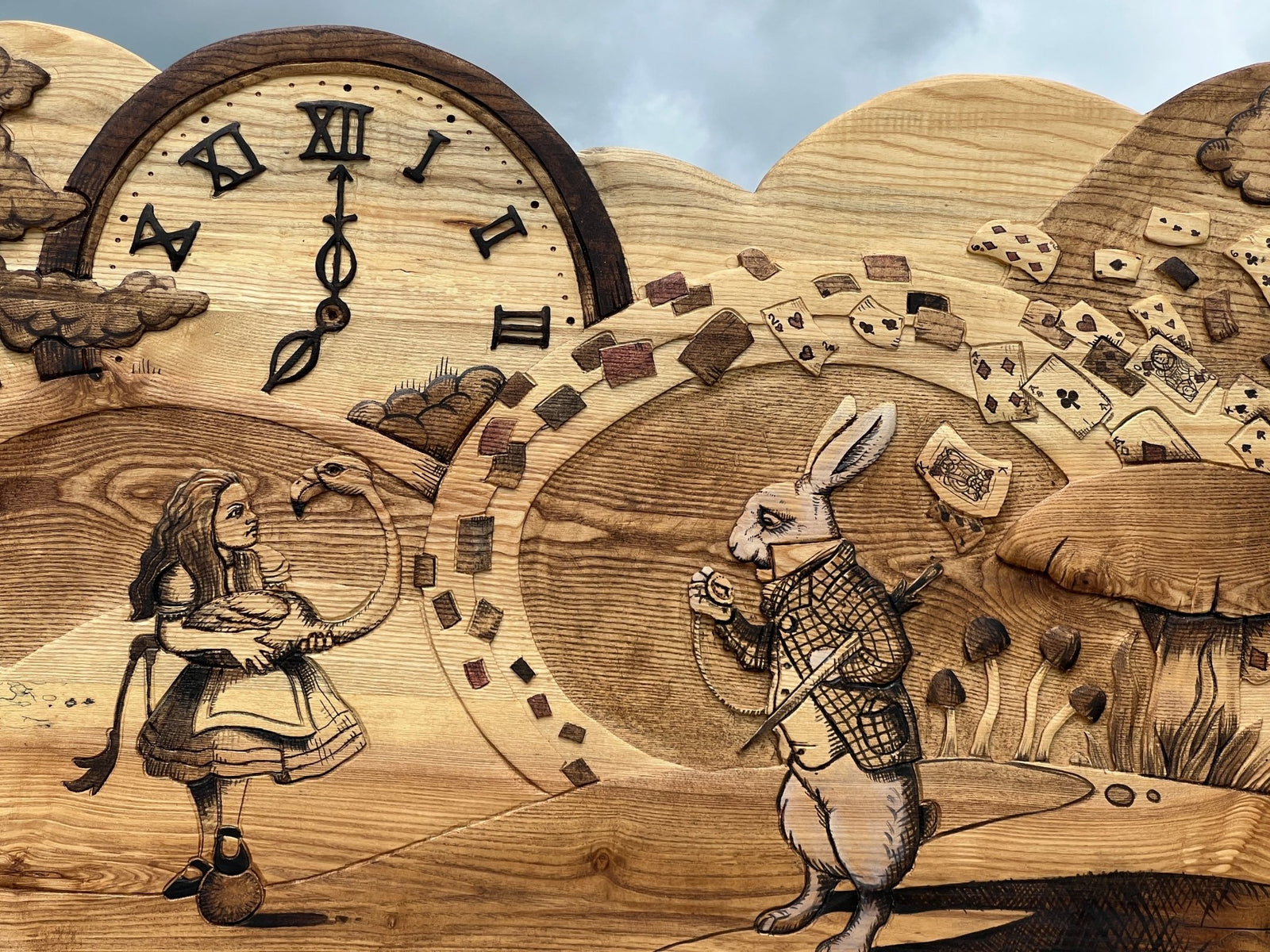 Close-up of clock, White Rabbit, and Alice details on wooden bed headboard — handmade, Wales