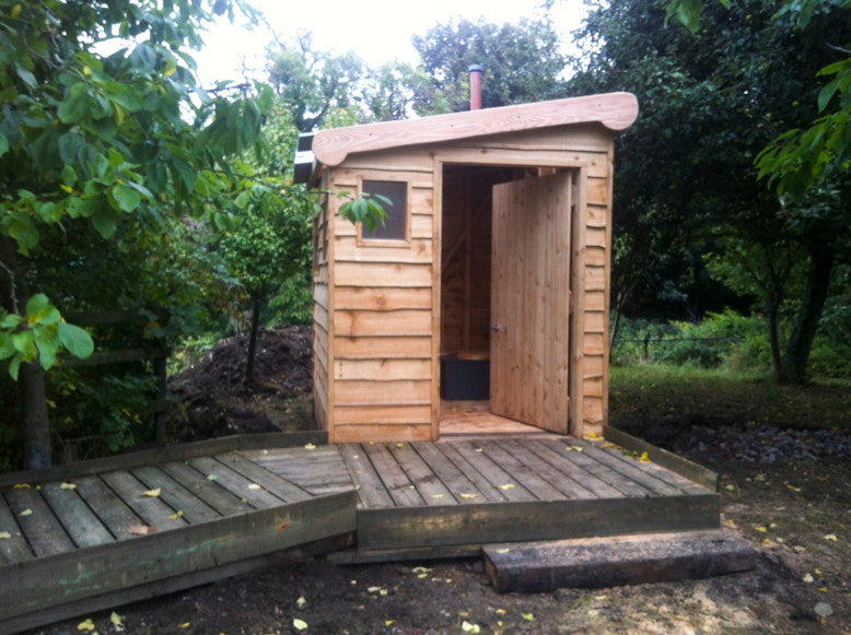 Toilettes à compost avec extérieur en bois et rampe d'accès dans la forêt