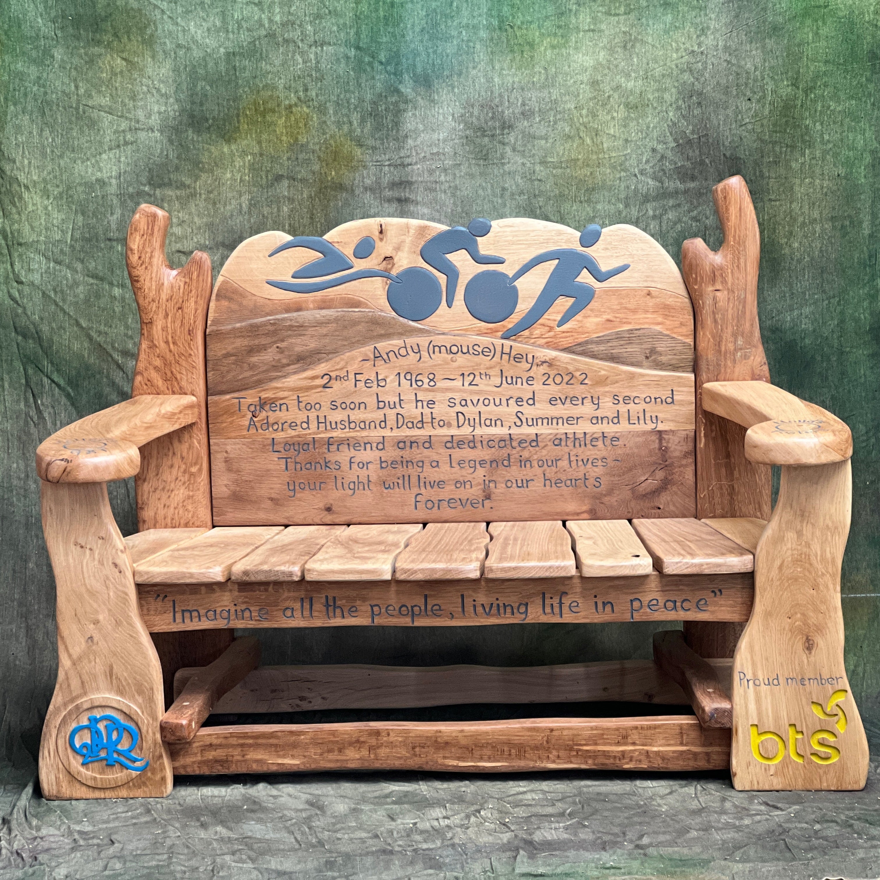 Handcrafted oak memorial bench with wheelchair sport carving, personalised tribute text, and painted QPR and BTS logos.

