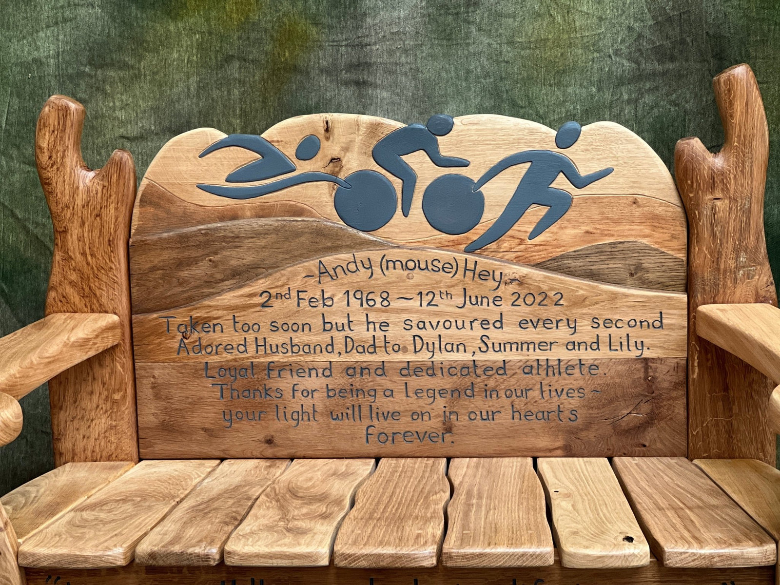 closeup view of memorial bench showing carved armrest with BTS logo and engraved sun motif, part of a fully personalised tribute design.