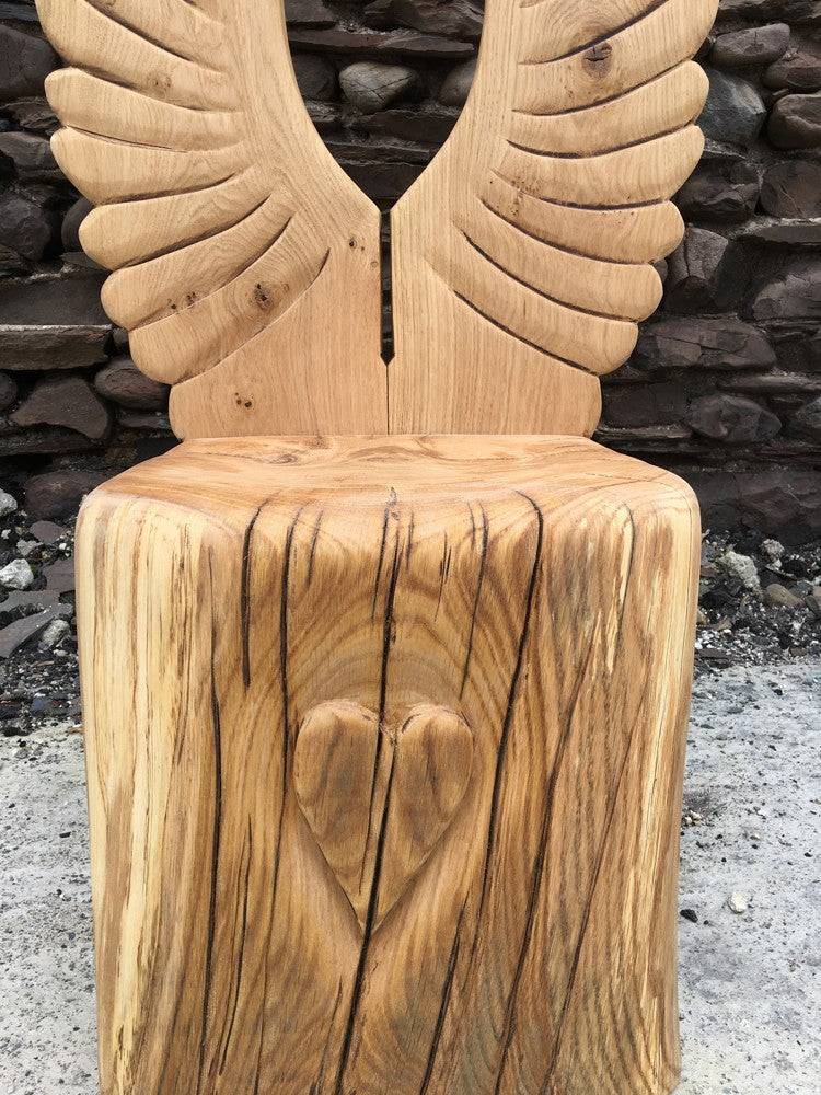 Carved oak angel story chair in garden setting — handmade storytelling furniture for schools, Wales