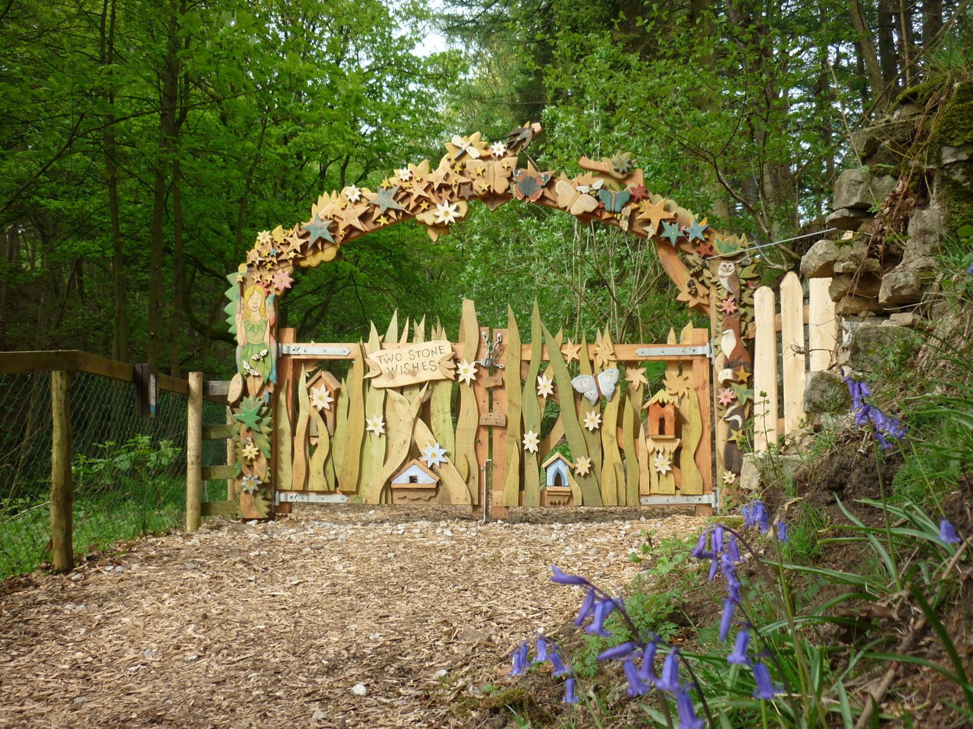 Wooden fairy gate in a forest setting with flowers in the foreground