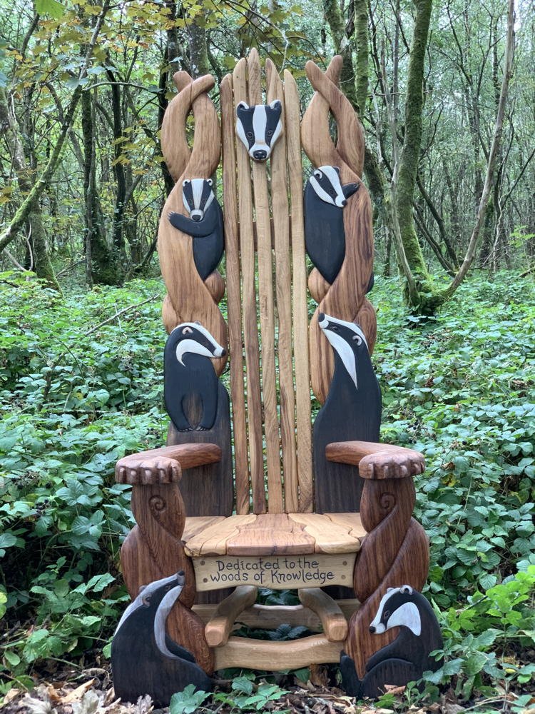 Handcrafted badger storytelling chair in forest setting — carved oak reading throne for schools, Wales