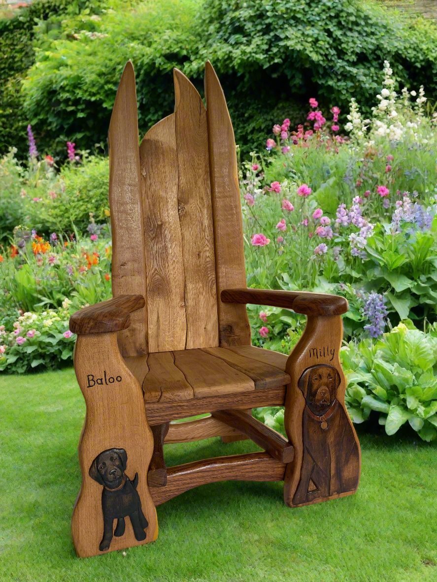 A handmade wooden chair with detailed dog carvings of Baloo and Milly, displayed in a lush garden setting surrounded by vibrant flowers, highlighting its natural and artistic appeal.
