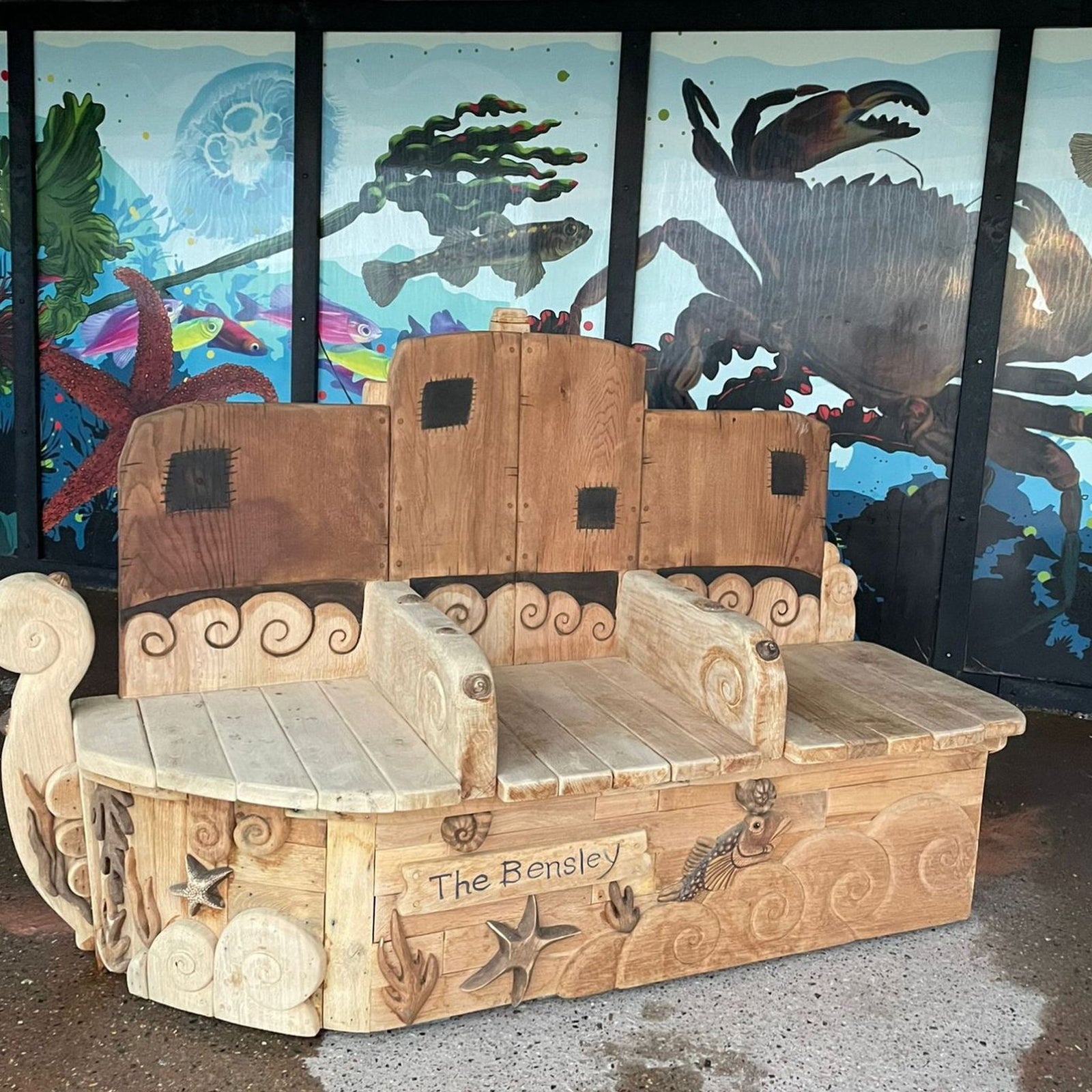 Front view of The Bensley hand-carved solid oak boat bench with nautical carvings and The Bensley name on hull