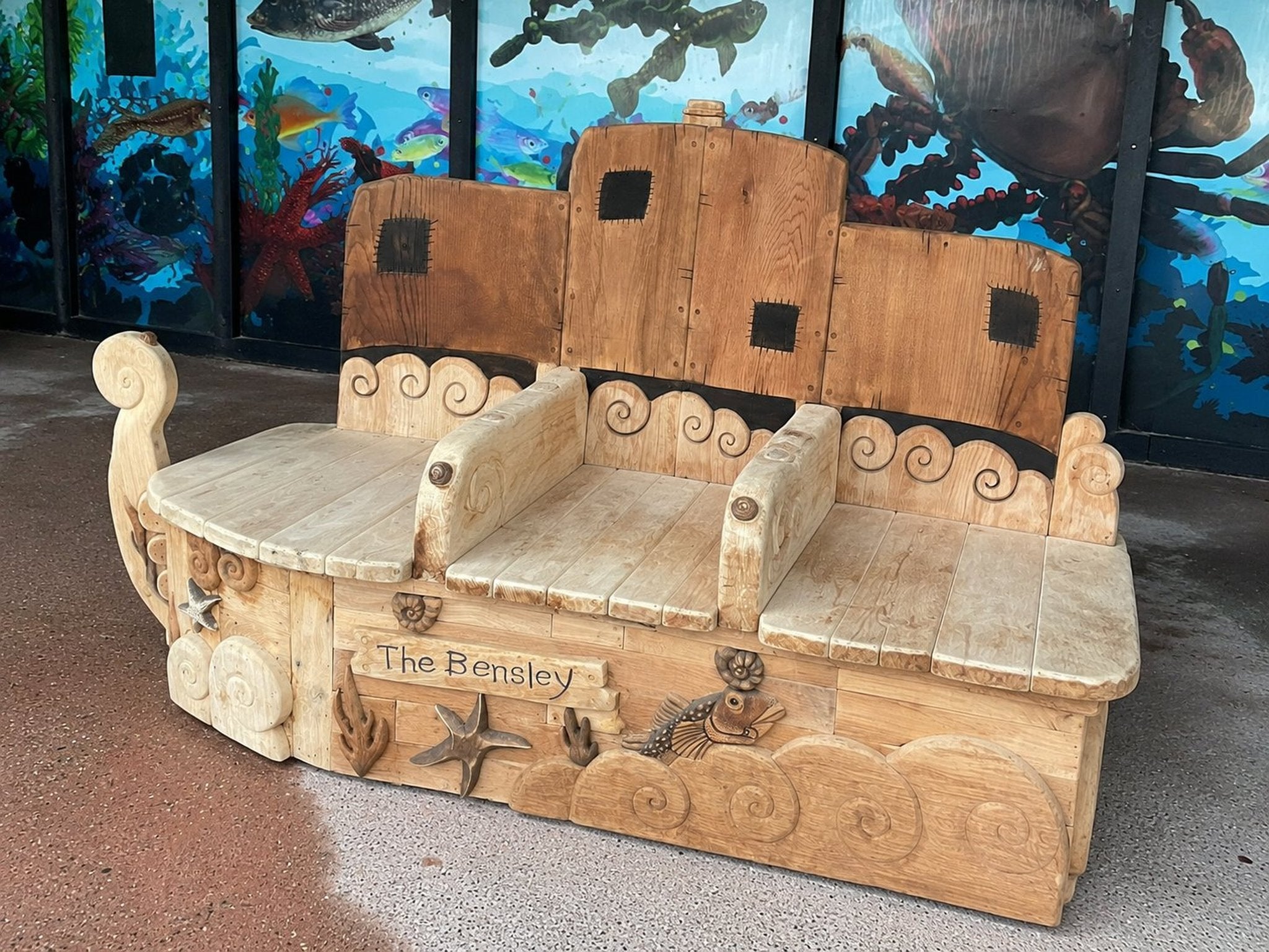 Three-quarter rear view of The Bensley carved oak boat bench showing wheelhouse backrest and wave details