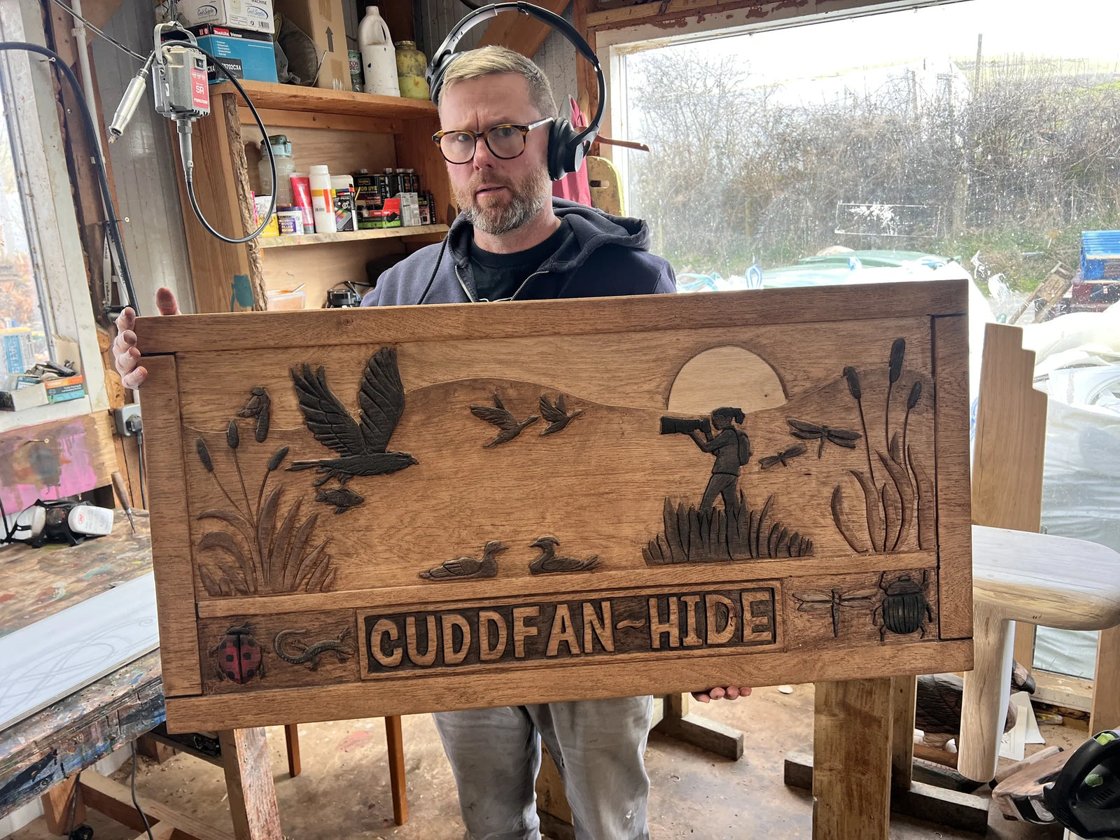 Craftsman holding the hand-carved oak Cuddfan Hide sign fresh from the FreeRangeDesigns workshop in Wales