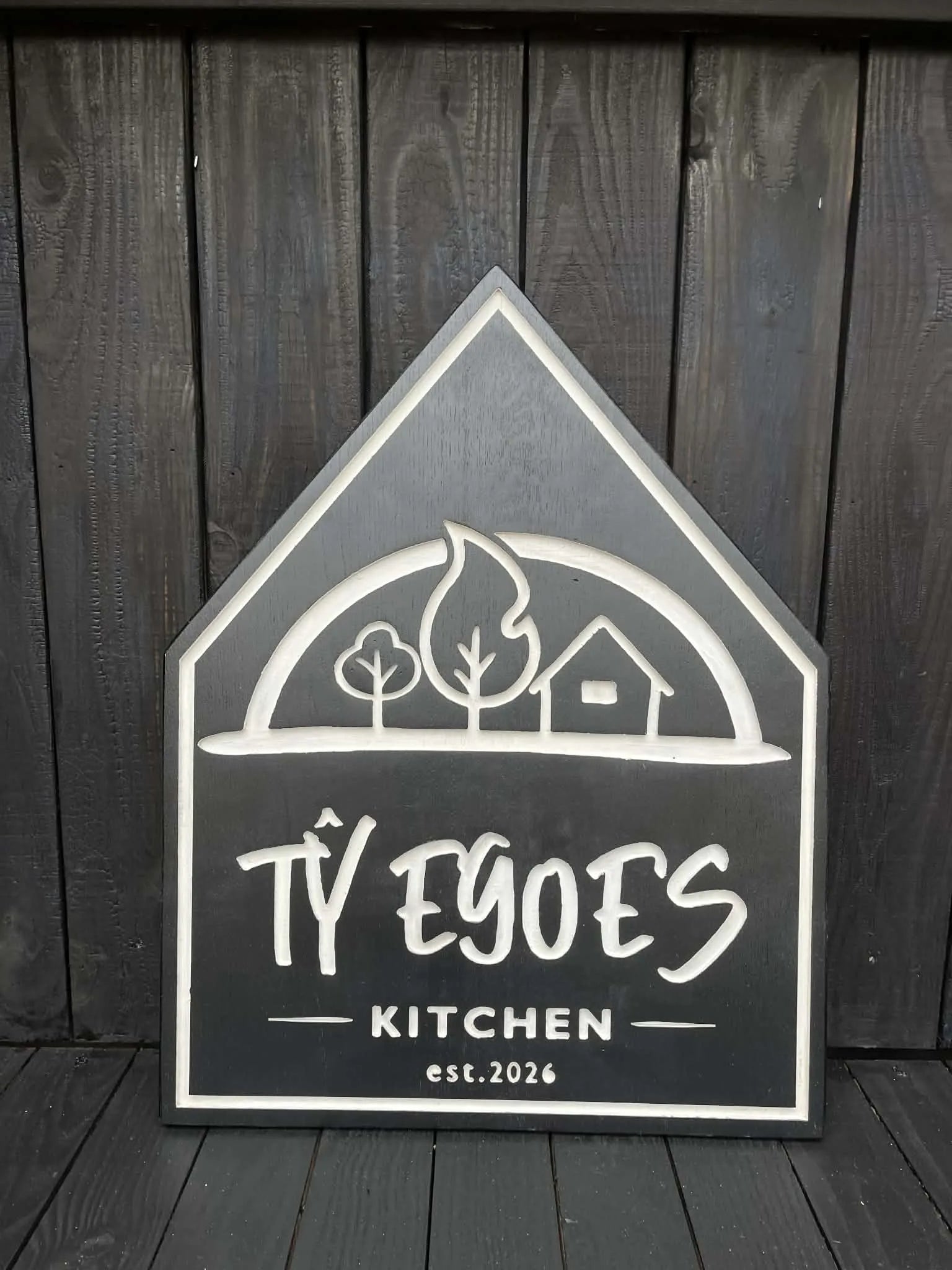 Front view of bespoke engraved solid oak sign with charcoal painted background and natural wood engraved design