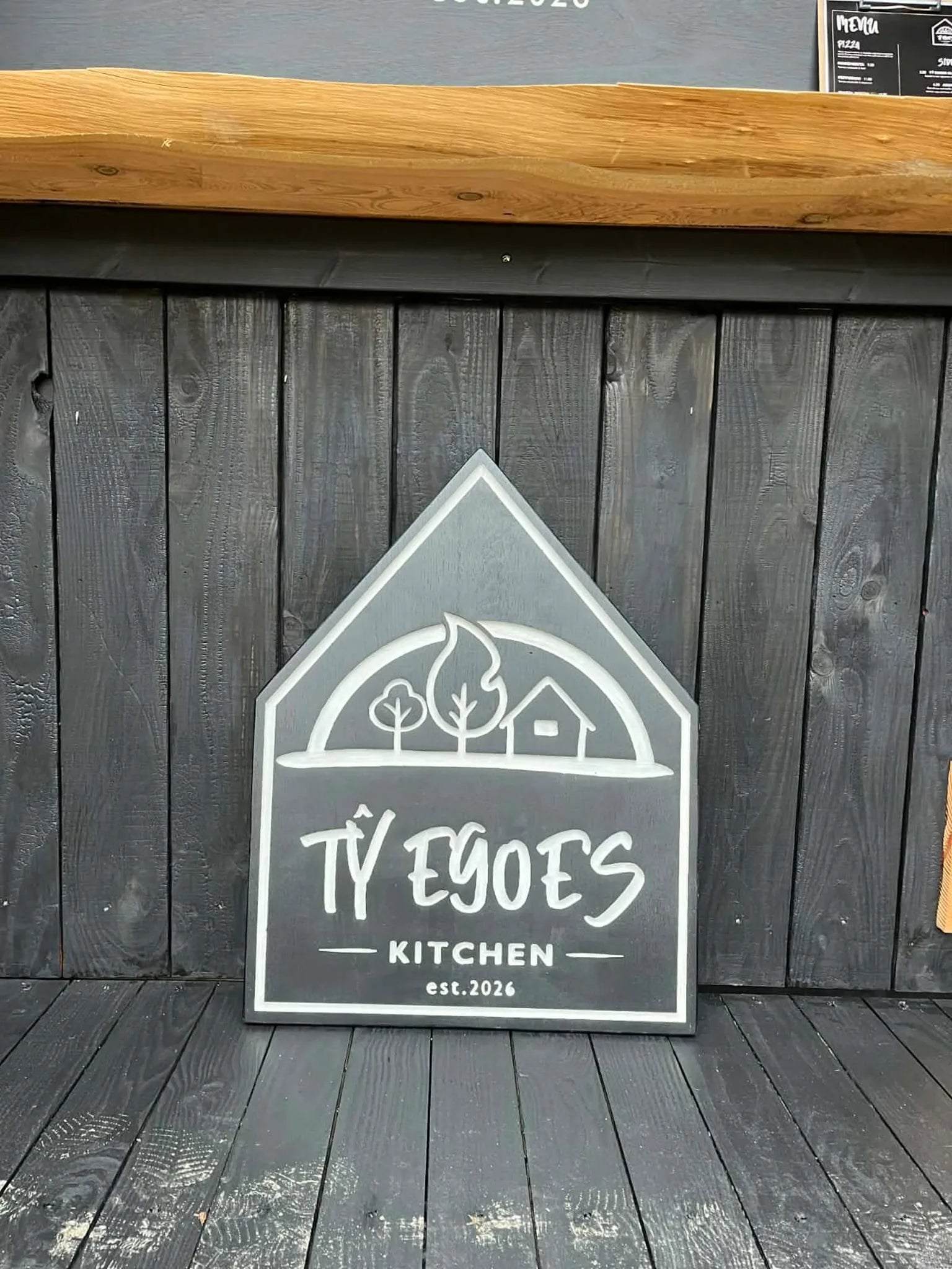 Custom engraved oak sign in situ at a food stall — bespoke wooden business signs handmade in Machynlleth, Powys