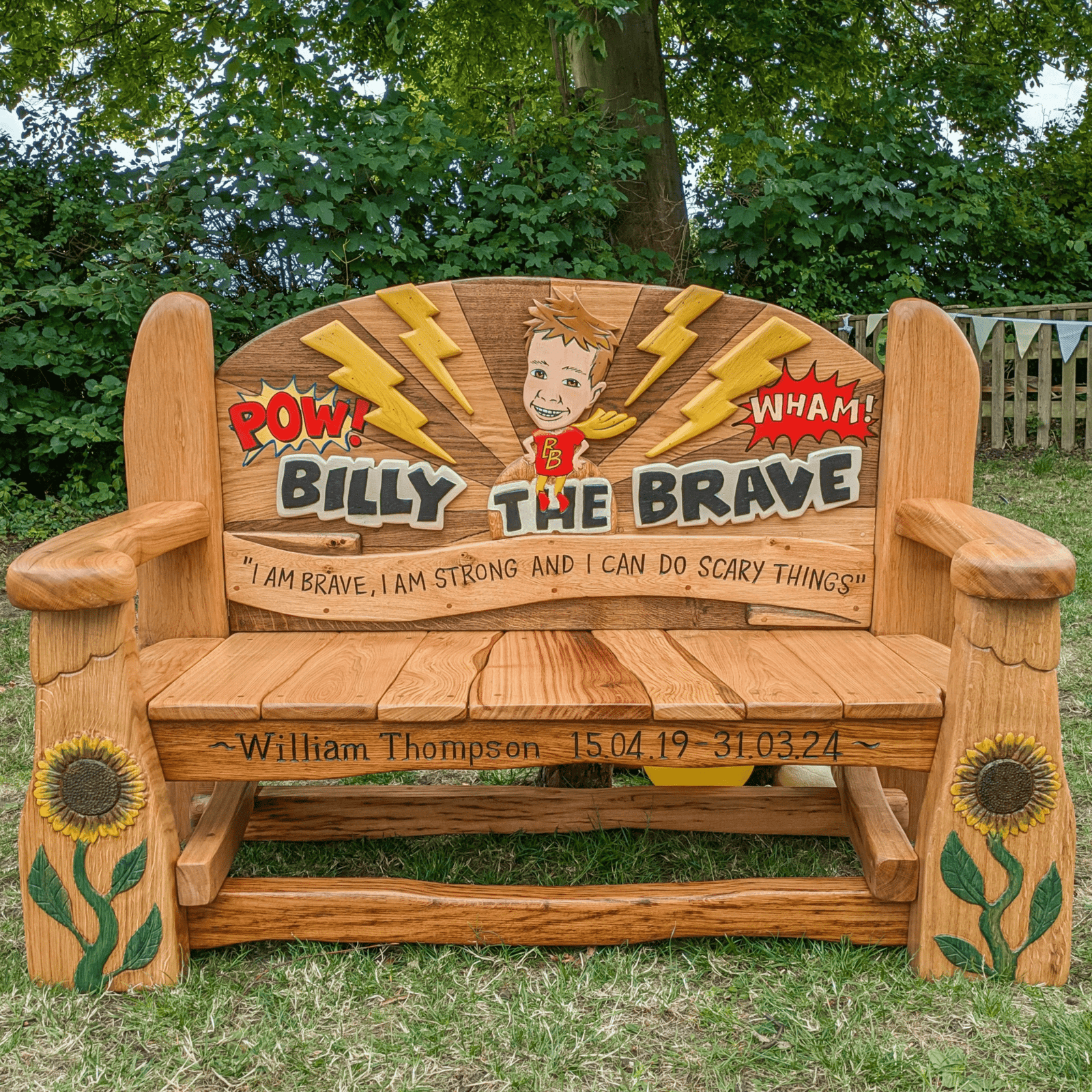 A handcrafted wooden memorial bench for Billy, featuring vibrant sunflowers, lightning bolts, and playful comic-style designs — handmade, Wales