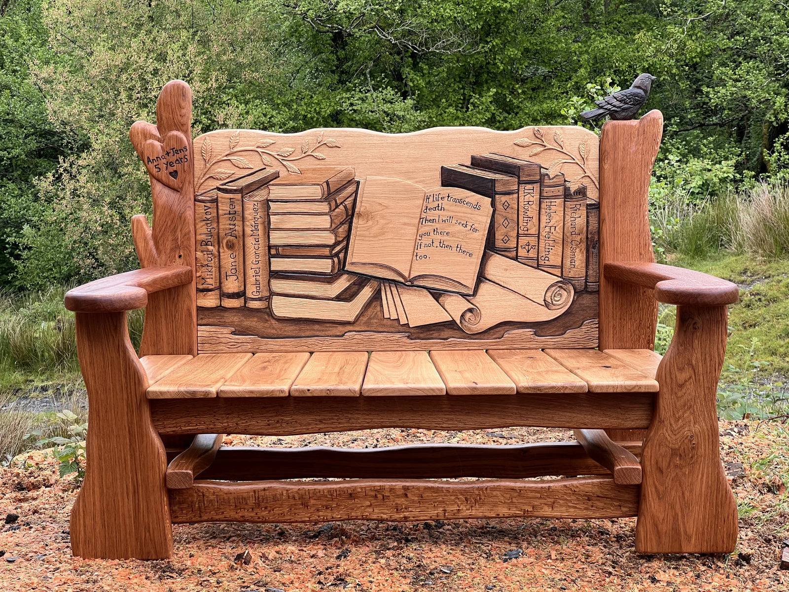 Front view of the carved oak book bench with a stack of books and open book on the backrest