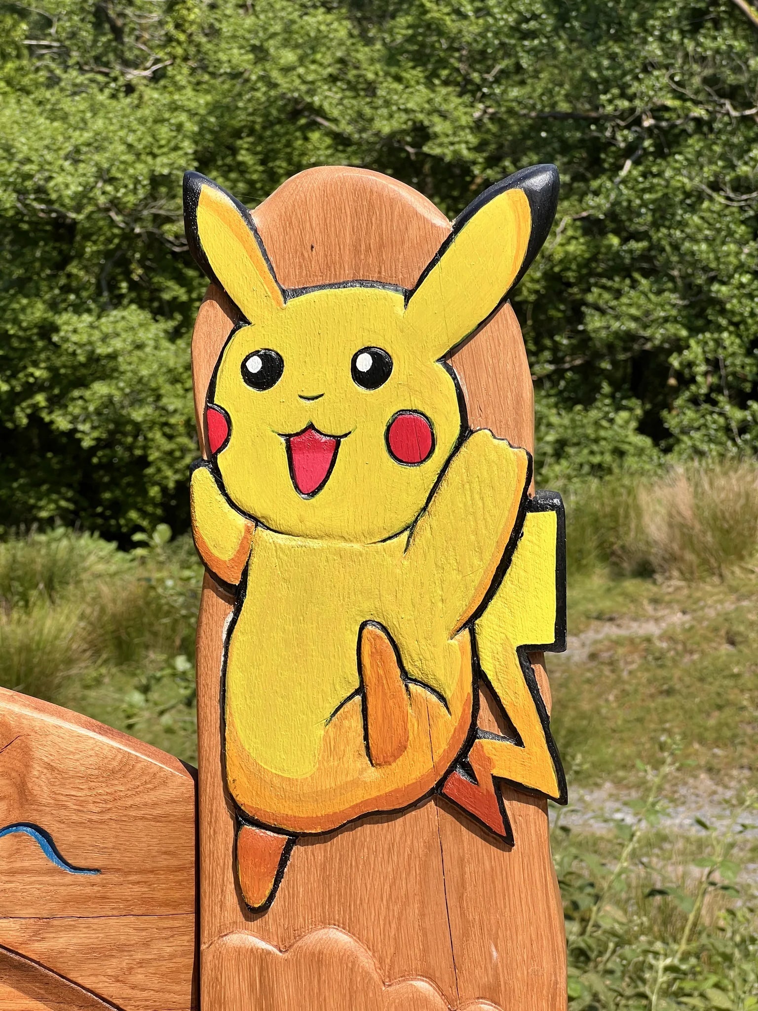 Hand-painted Pikachu carved onto the top post of the oak memorial bench