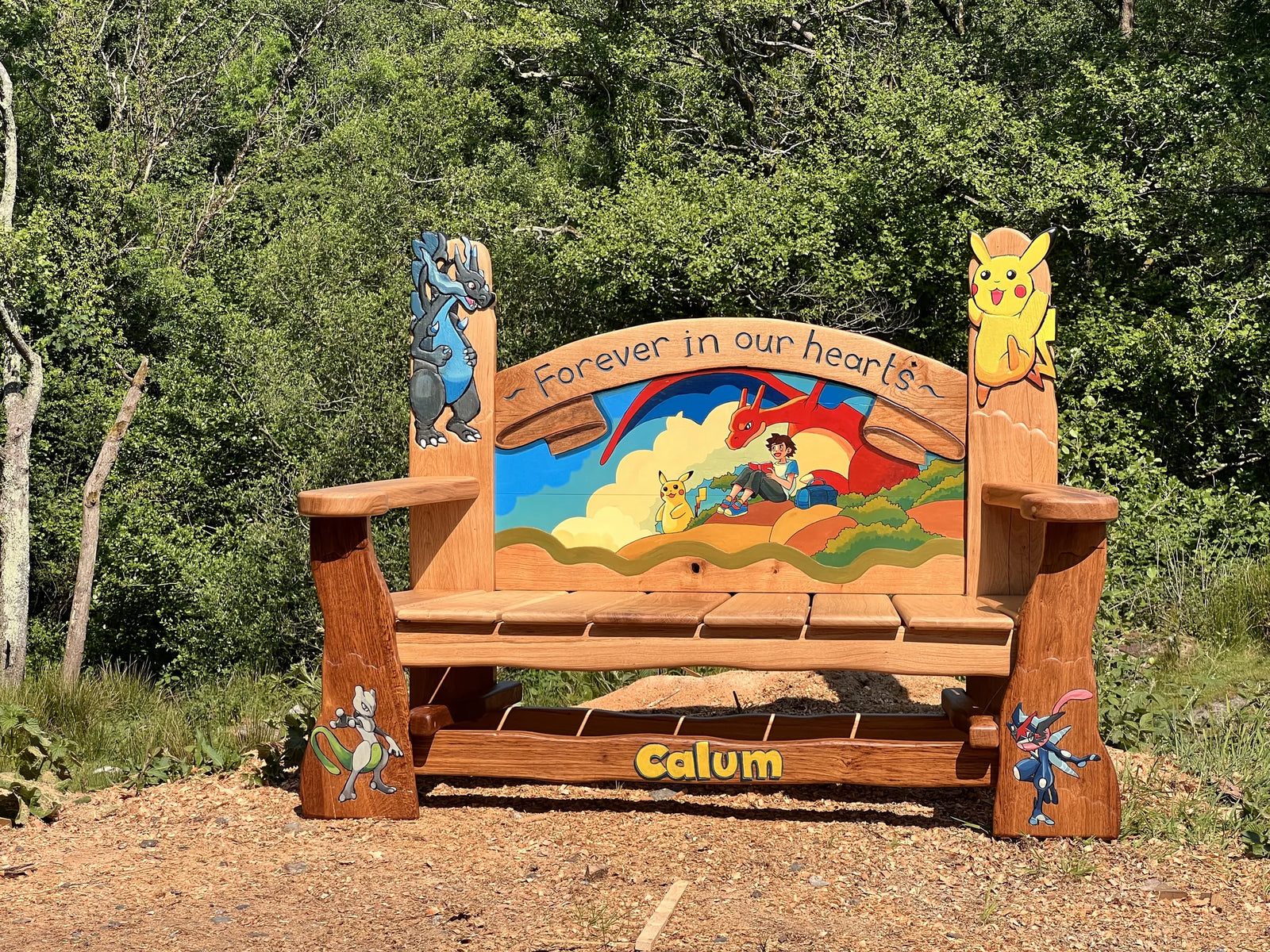 Front view of the Pokémon children's memorial bench in solid oak with colourful painted scene