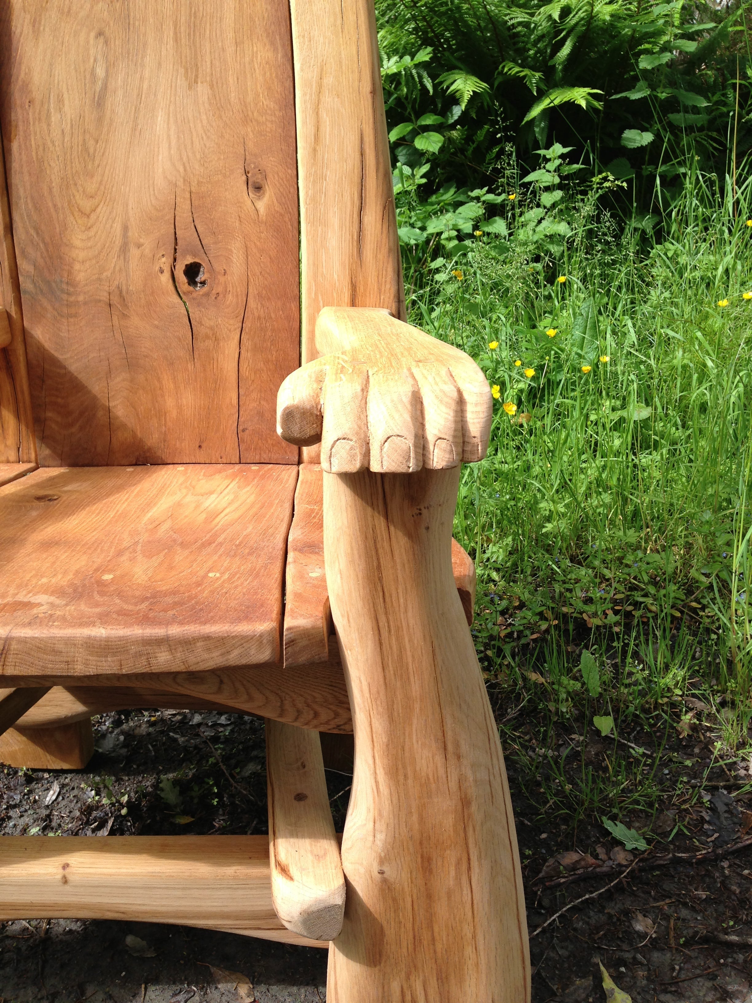 Gros plan sur l'accoudoir d'une chaise en bois avec un motif de patte