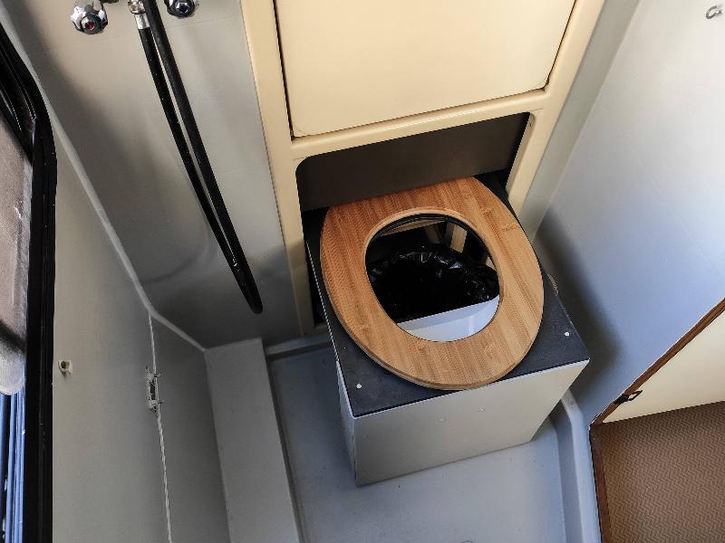 Compact composting toilet with a bamboo seat, ideal for tiny homes and camper vans