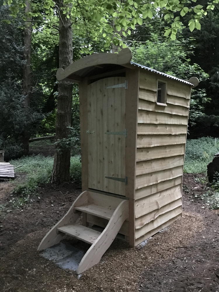 Compost toilet in wooded area at dusk