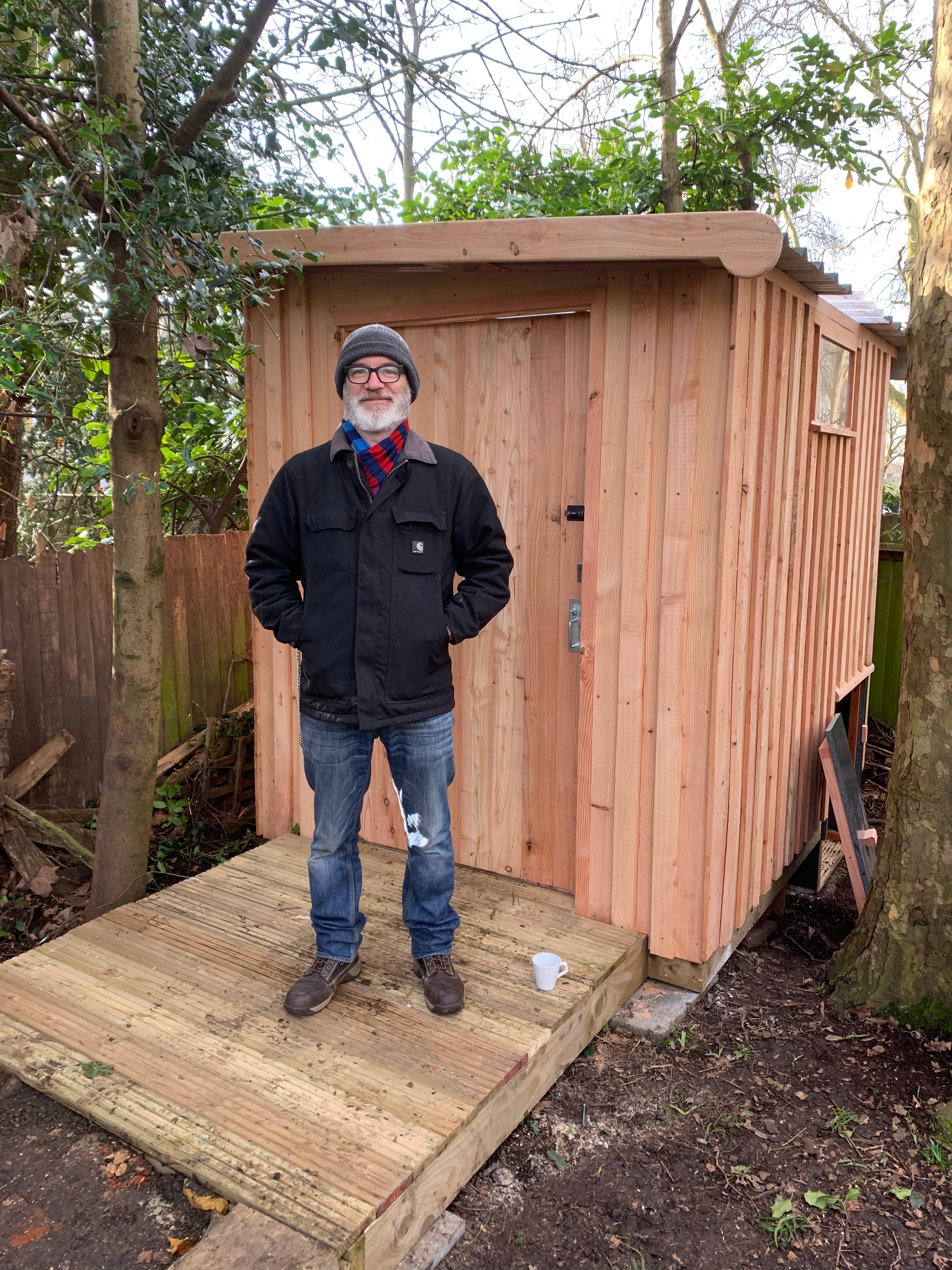 Man standing in front of a wooden compost toilet