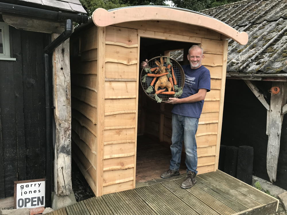 Man holding artwork in front of compost toilet