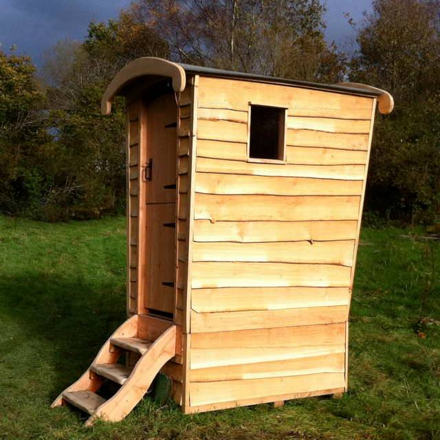 Komposttoilettenhäuschen aus Holz auf einem Feld