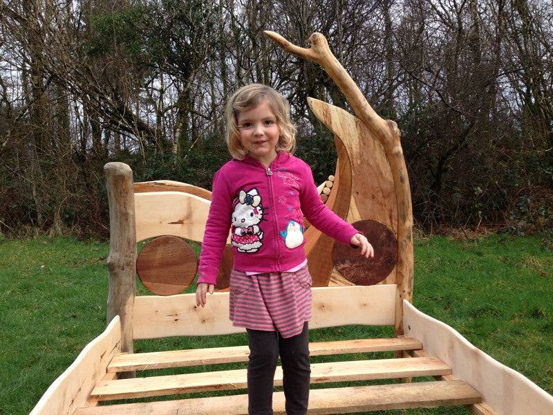 Child standing on handcrafted driftwood bed frame