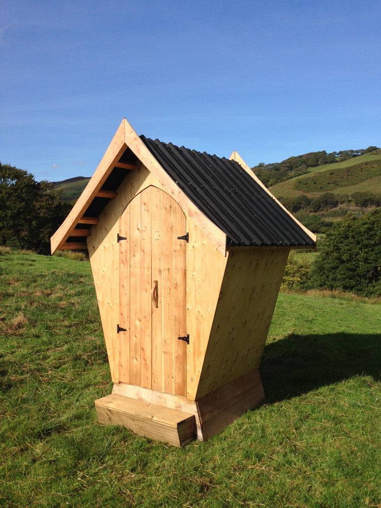 Handcrafted designer composting toilet for glampsite — eco-friendly outdoor facility in a field