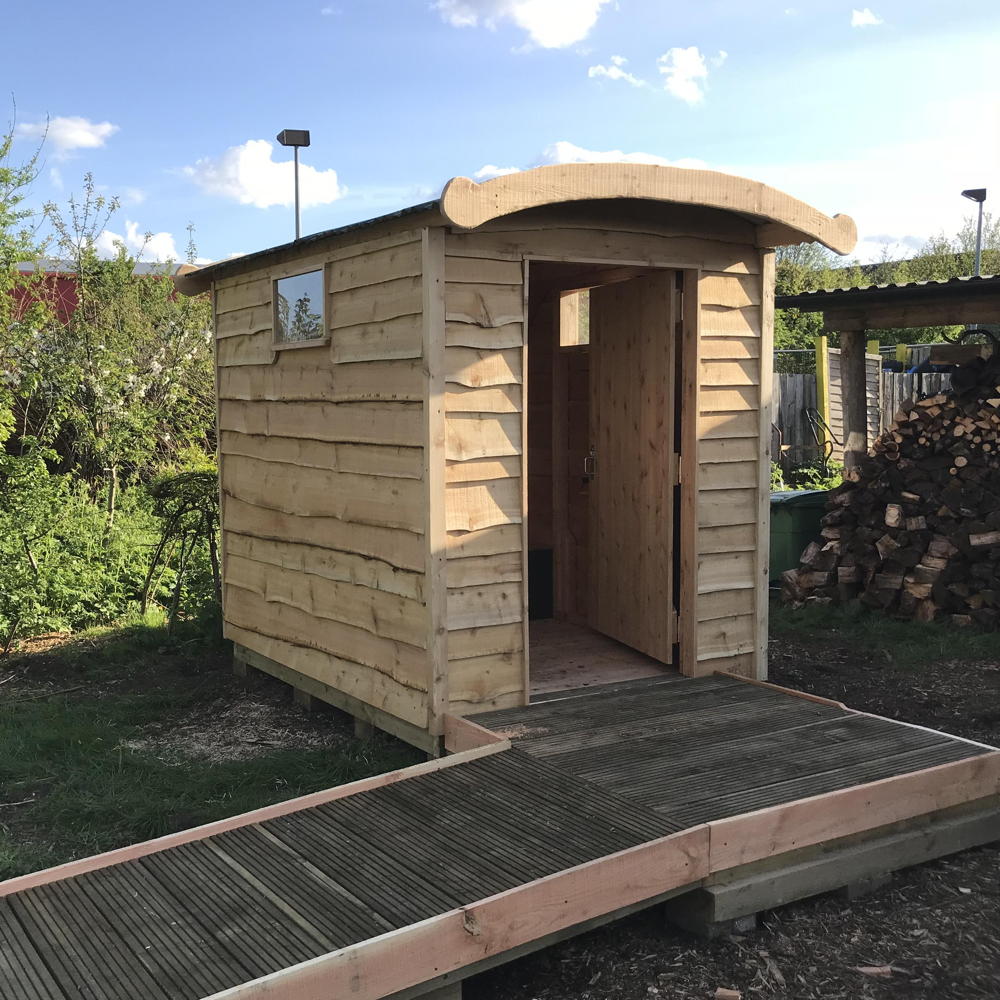 Disabled Access compost toilet with wheelchair ramp in garden setting