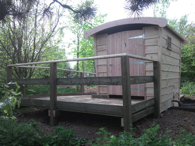 Compost toilet with wooden deck and railing