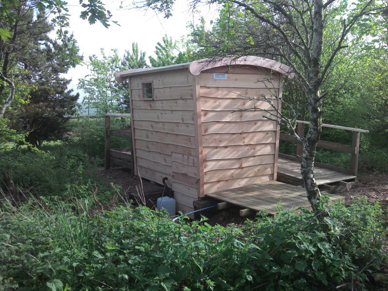 Back view of compost toilet with wooden exterior