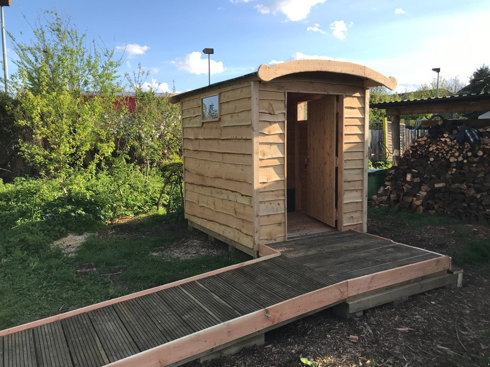 Wooden compost toilet with ramp access in garden