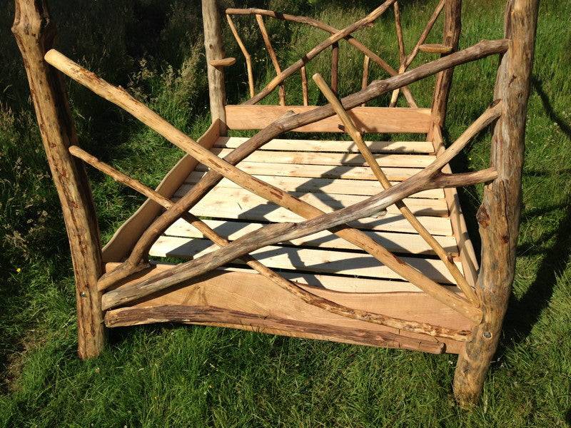 Driftwood four poster tree bed outdoors — handmade solid oak bedroom furniture, Wales