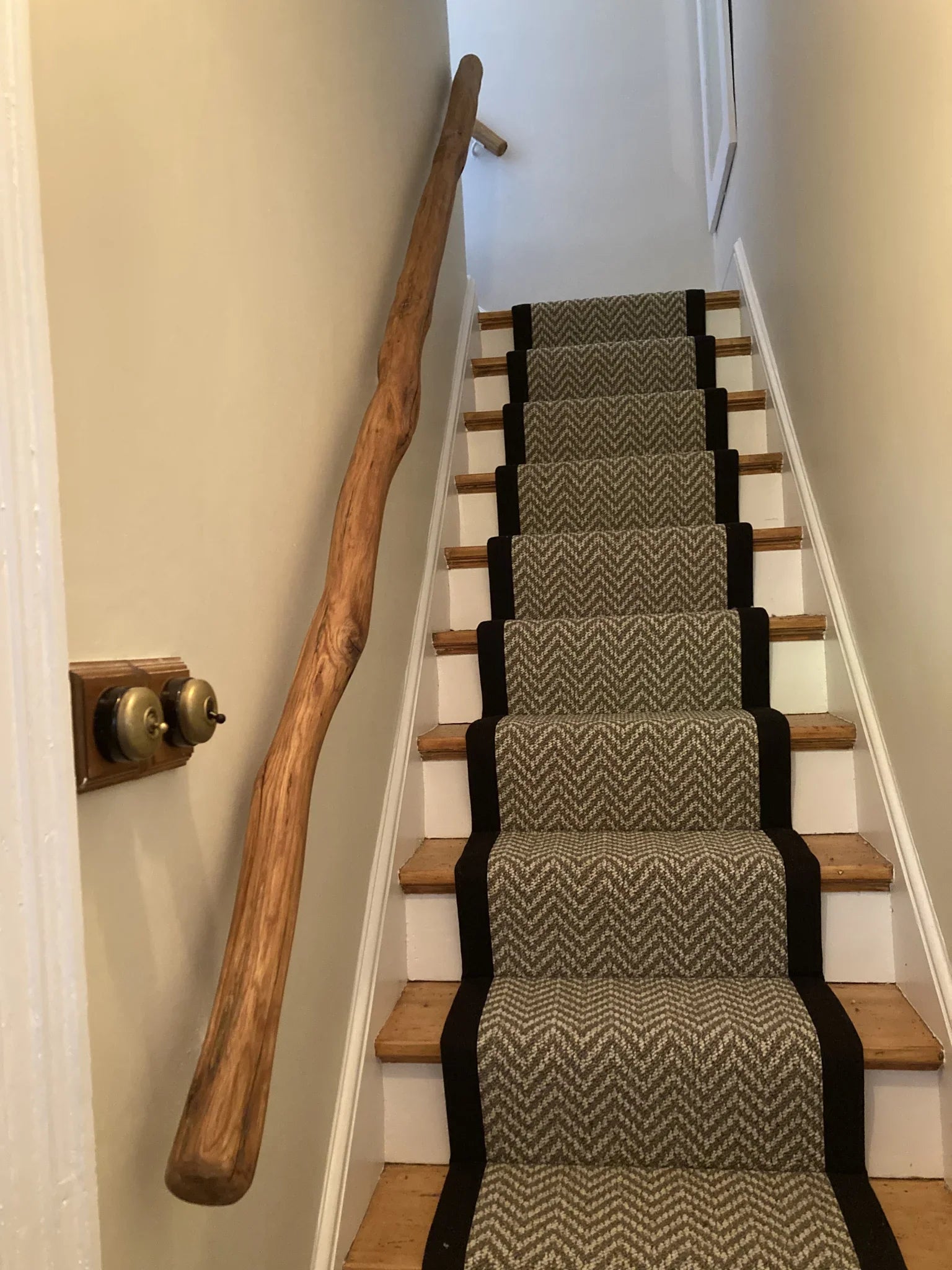 Rustic oak branch handrail on a staircase with herringbone runner — handmade natural wood banister