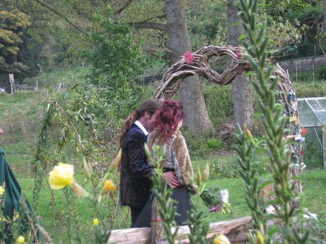 Couple embracing by driftwood arch in garden