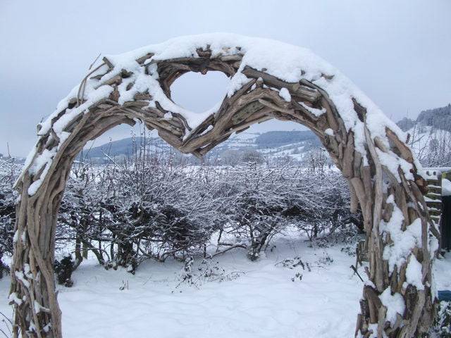 Arche en bois flotté recouverte de neige dans un paysage d'hiver