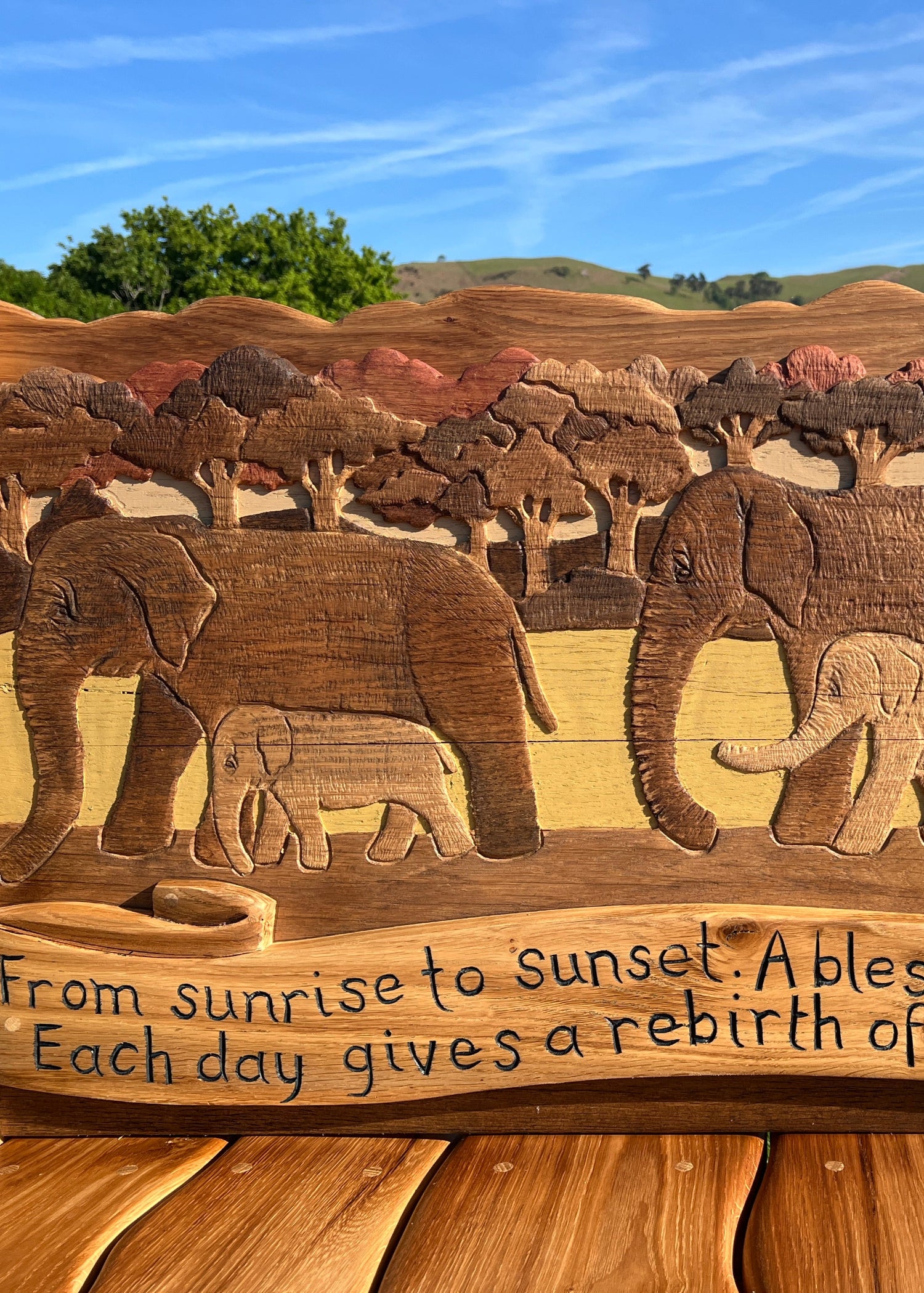 Close-up of elephant carving and engraved message on backrest of bespoke oak memorial bench.