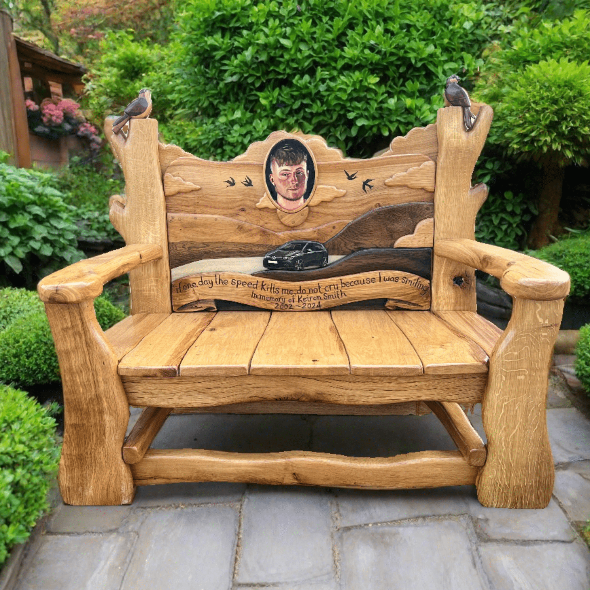 A beautifully handcrafted wooden memorial bench with personalized carvings, featuring a backrest with intricate details and symbolic birds, designed for gardens or outdoor remembrance spaces.


