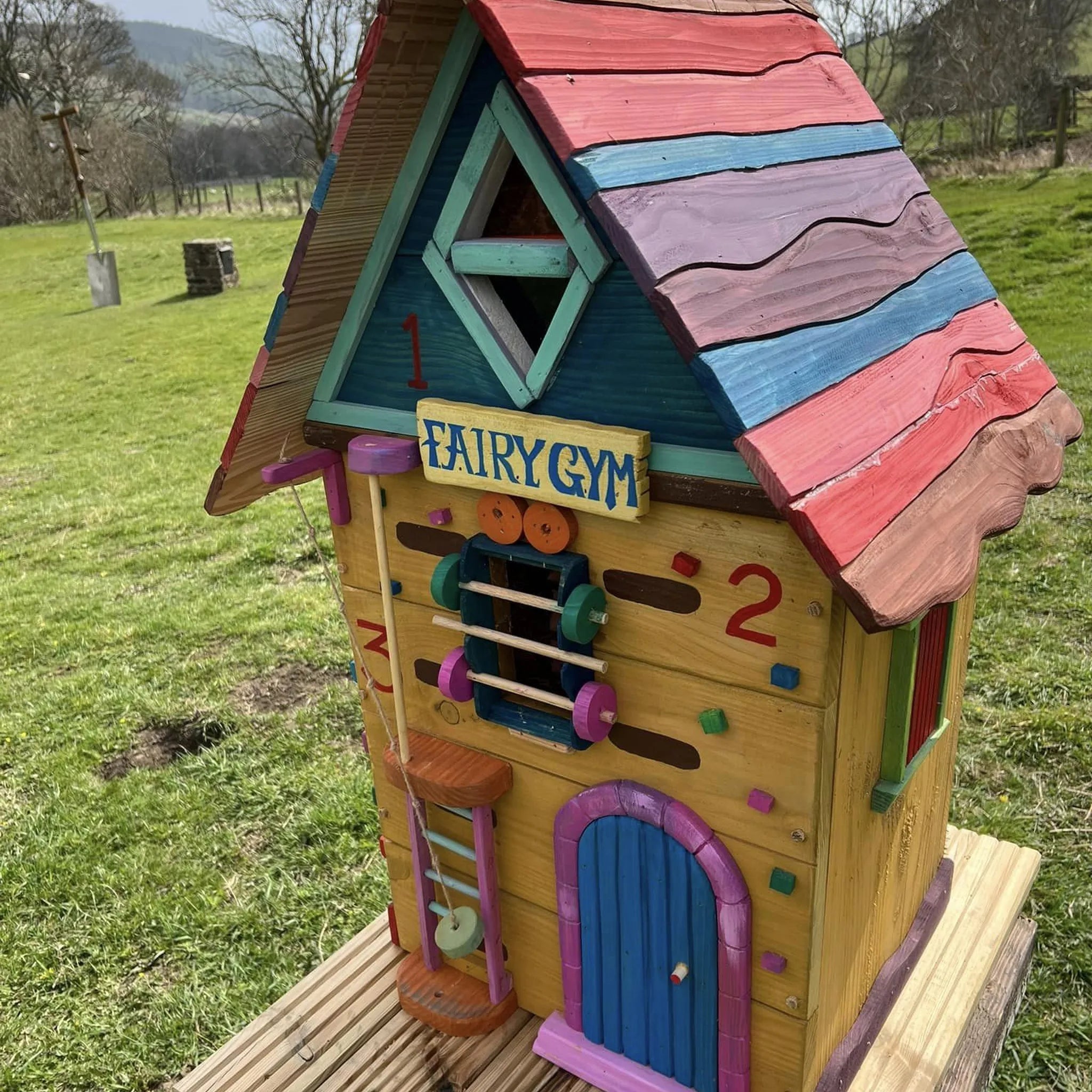 Handmade fairy gym house with hand-painted exercise equipment, climbing frame and tiny sports-themed windows