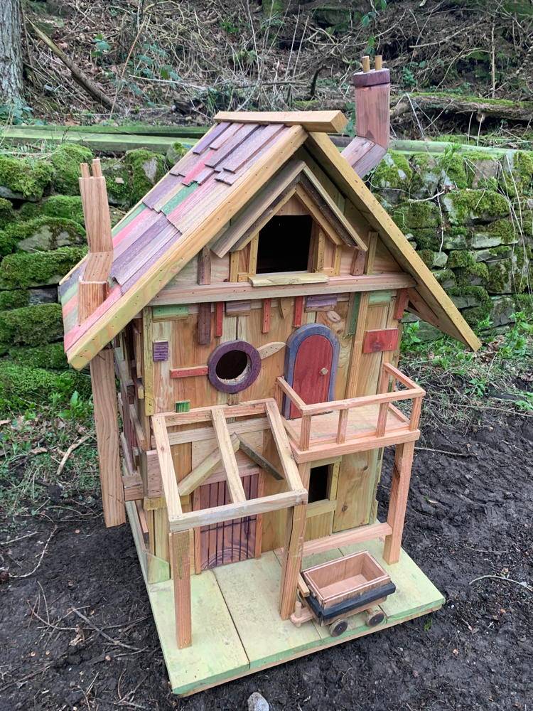 Hölzernes Feenhaus mit einem kleinen Wagen