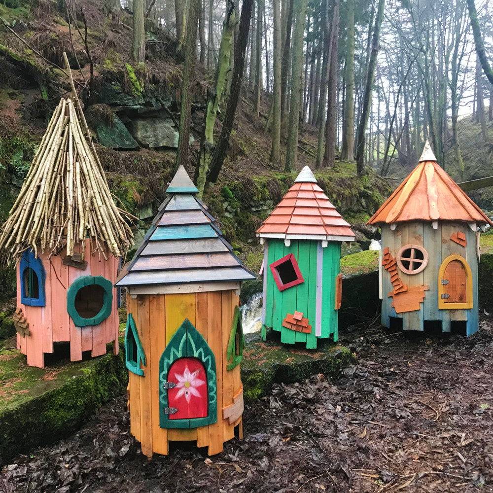 Colorful fairy houses on the ground in a wooded area