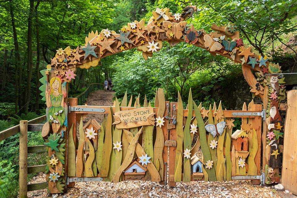 Decorative wooden archway with fairy-themed elements in a forest setting