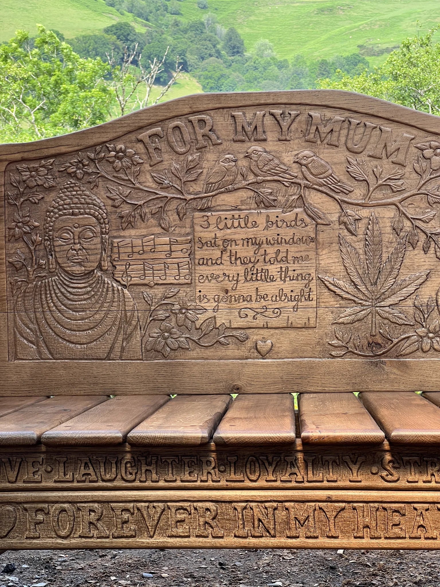 Detail of the hand-carved Buddha and birds on the oak memorial bench backrest