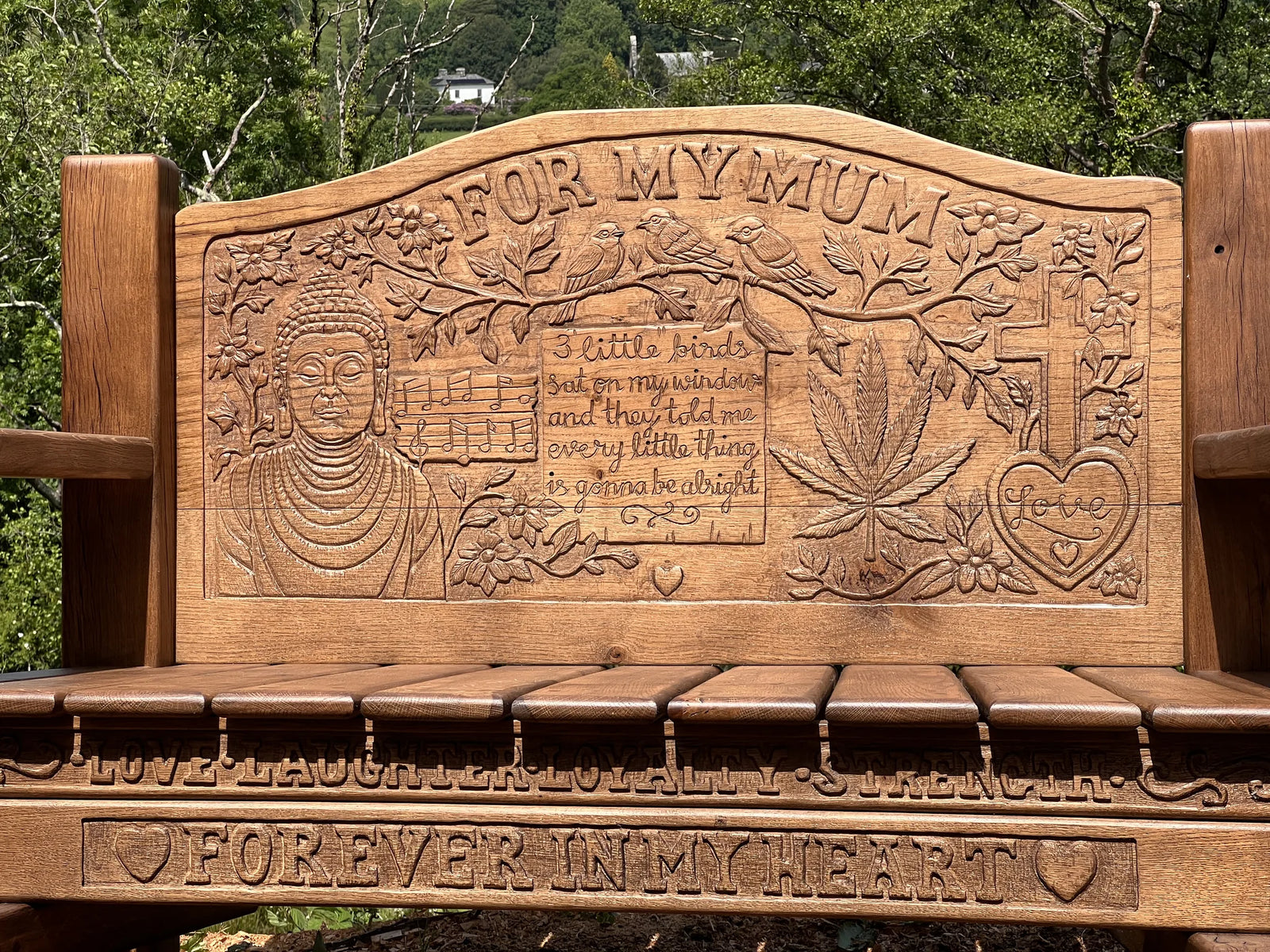 Carved oak backrest with Buddha, birds, leaves and personal wording on the memorial bench