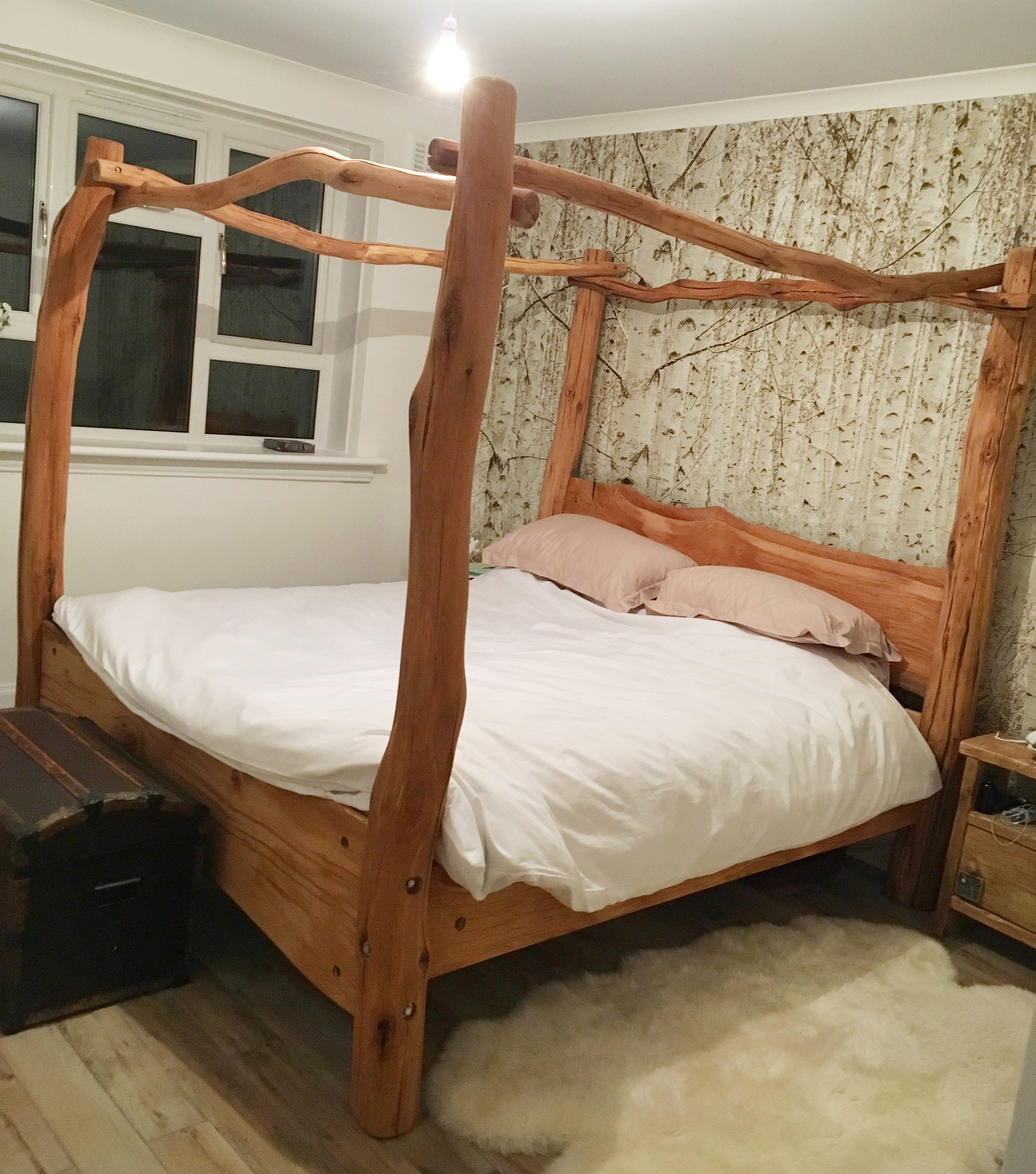 four poster bed with green wallpaper in background