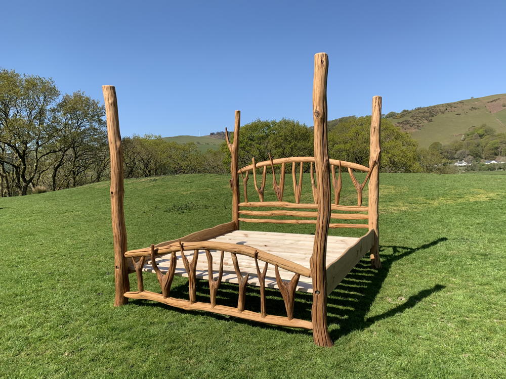 Handcrafted oak four poster bed on grass