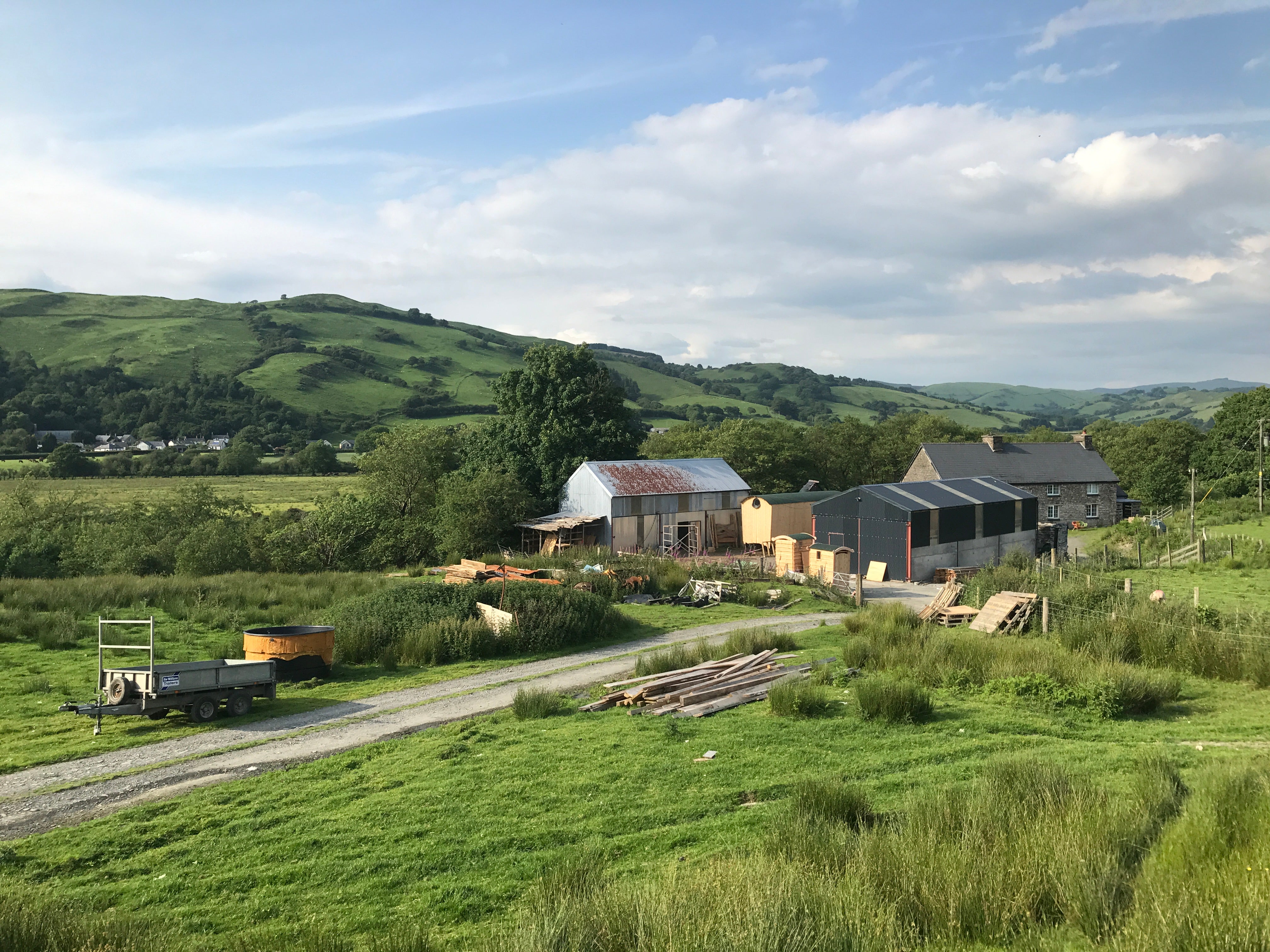 Scenic view of the Free Range Designs workshop nestled in the green hills of West Wales, showcasing rustic barns, open fields, and natural surroundings