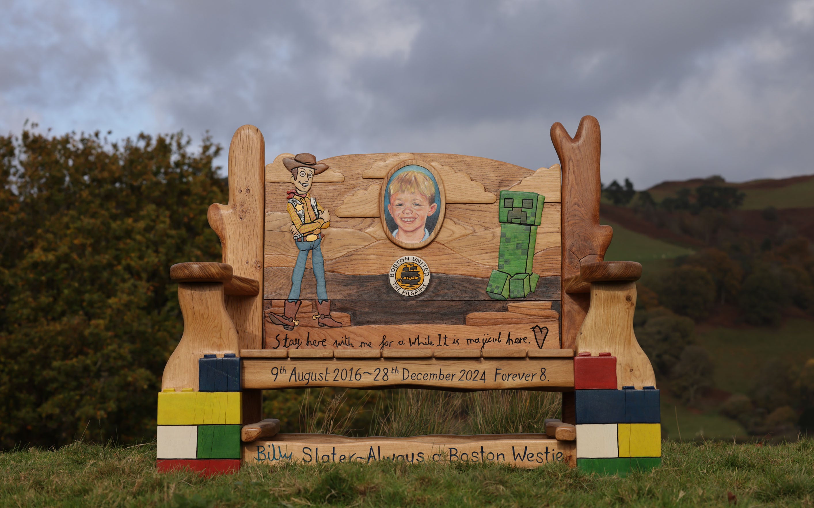 Wooden memorial bench with cowboy design and scenic background